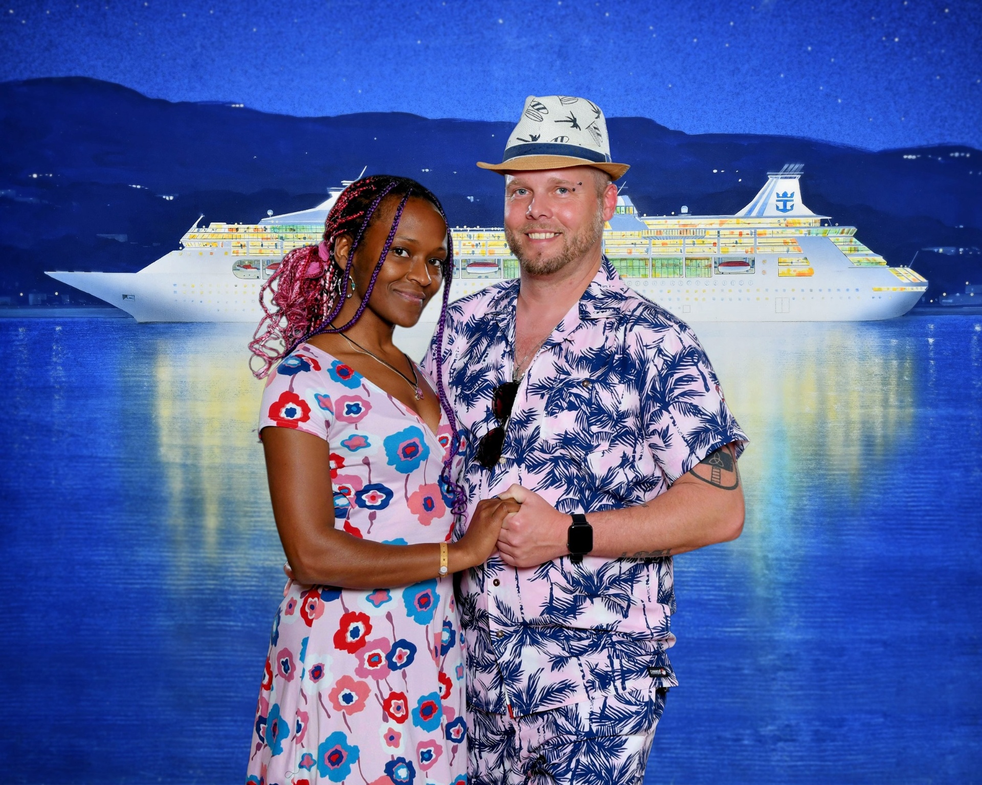 Shane and Kerry on a formal night aboard the Royal Caribbean cruise ship, posed in front of a backdrop of the ship at night